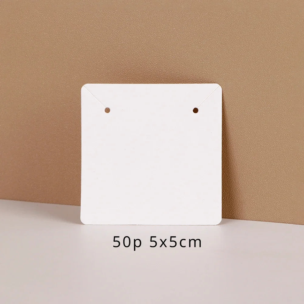 A white square jewelry display card is shown against a beige background with a measurement of 50p 5x5cm below it.