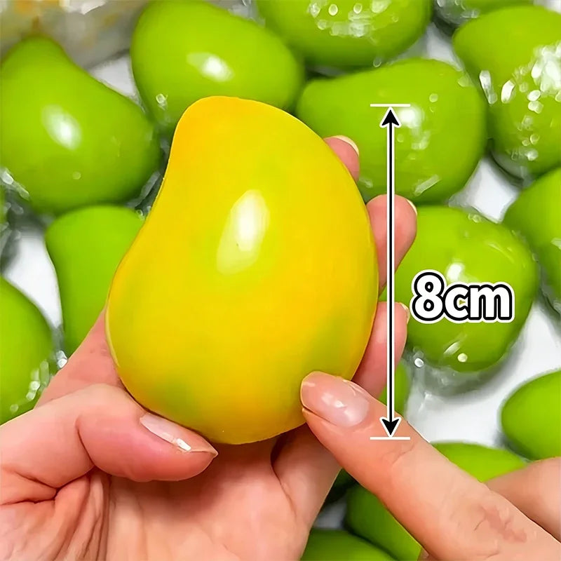 A hand holds a bright yellow color-changing mango squishy stress ball next to green ones.