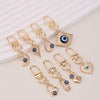 A set of gold-toned evil eye keychains with blue accents displayed on a white background.