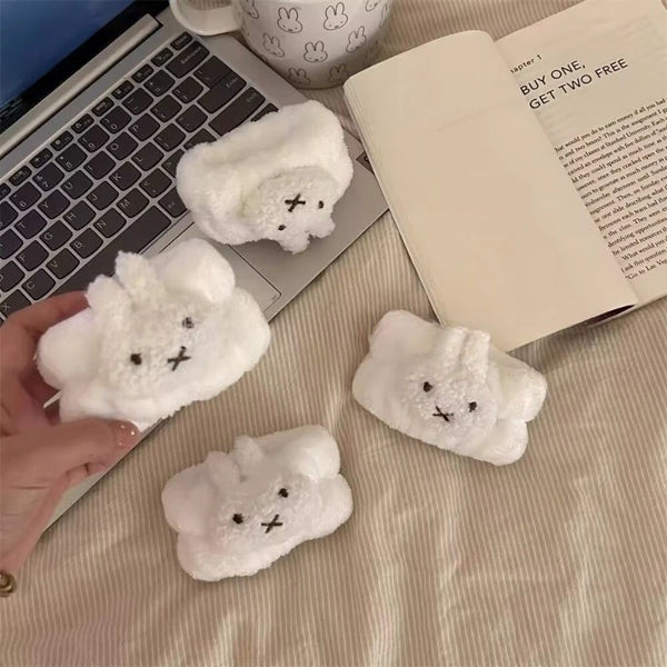 A white, fluffy Miffy waterproof face wiping wristband is shown next to a laptop and an open book.