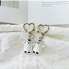 A set of two white penguin heart keychains attached to a silver-colored chain, displayed on a white textured cloth.