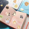 Gros plan d'un carnet rempli d'autocollants de chats mignons, représentant divers chats en différentes poses et couleurs.