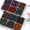A collection of round, glitter cat eye resin beads in various colors and shades arranged in small plastic compartments.