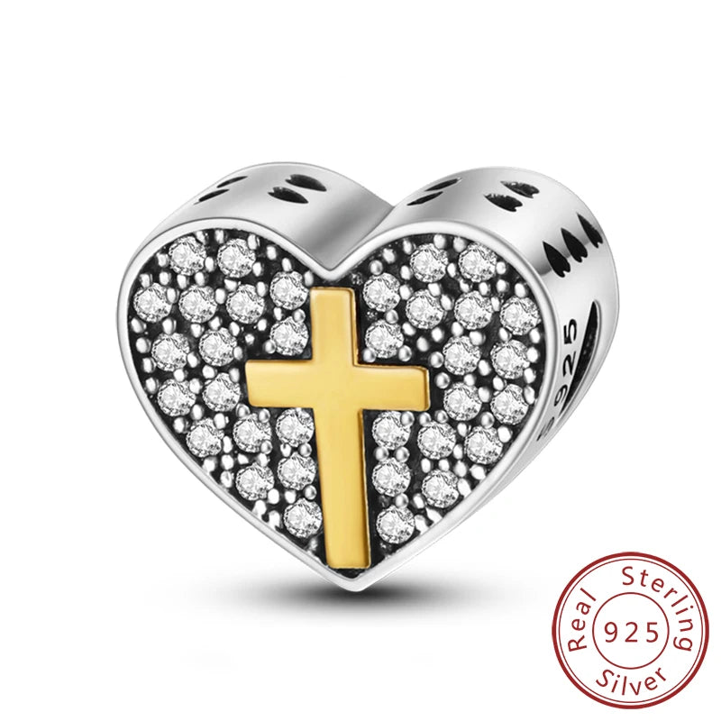 A sterling silver heart-shaped charm featuring a gold cross surrounded by clear and black stones.