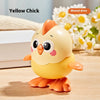 A yellow chick wind-up toy with orange accents sitting on a wooden surface next to white and floral elements.