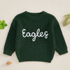 A dark green knit sweater for a baby or kid with white embroidered text spelling out Eagles
