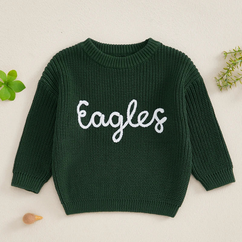 A dark green knit sweater for a baby or kid with white embroidered text spelling out Eagles