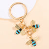 Gold-toned bee and flower enamel keychain with black and blue accents