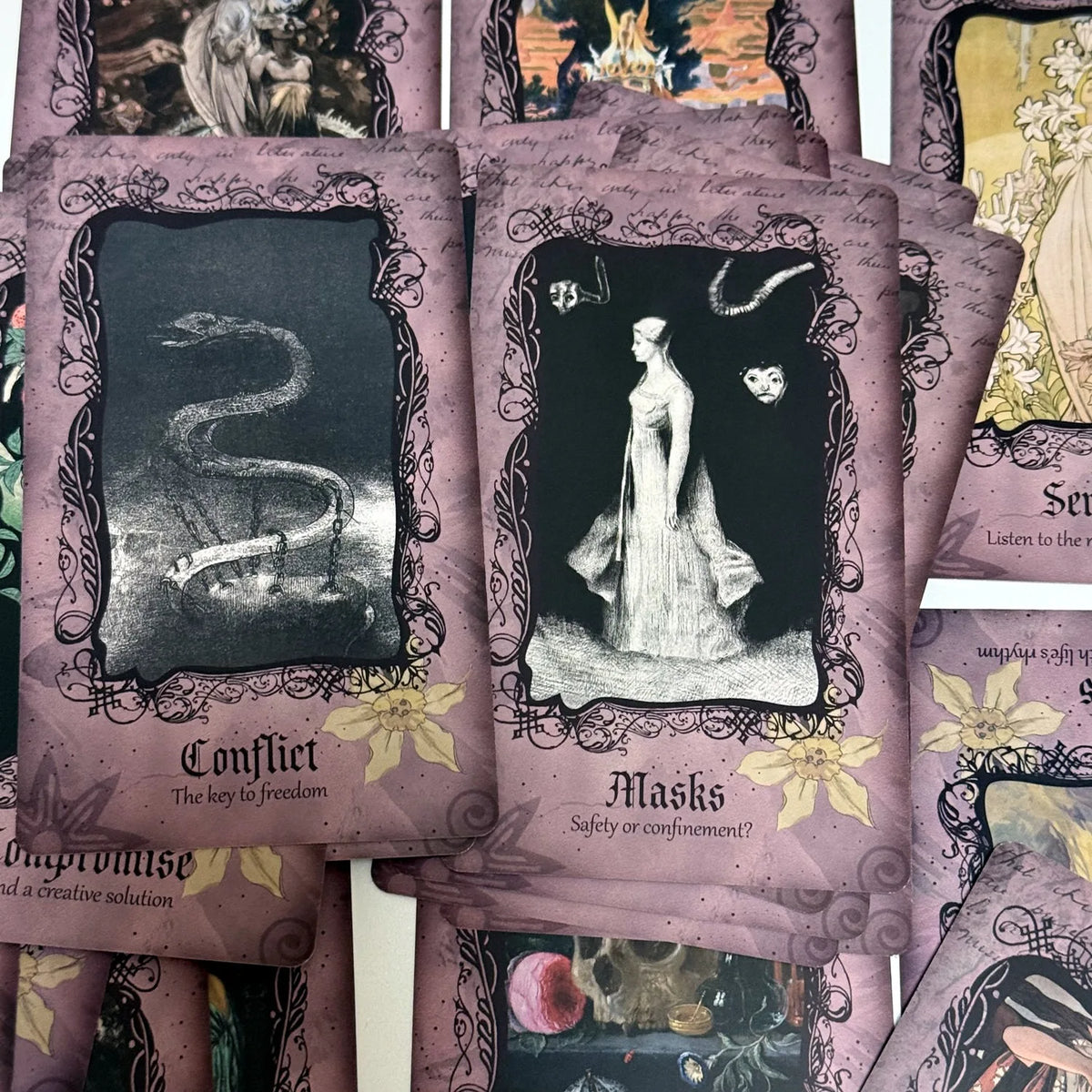 A collection of purple-toned oracle cards featuring black and white illustrations of serpents, figures, and masks.