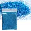 A sealed packet of bright blue holographic glitter powder next to a pile of loose glitter.