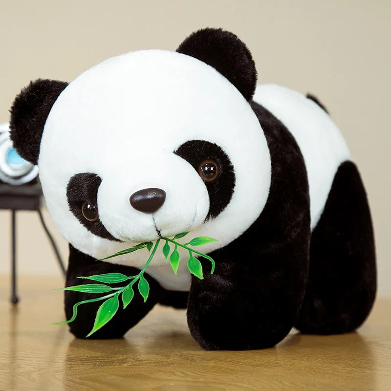 A black and white bamboo panda plush stuffed animal with green leaves.