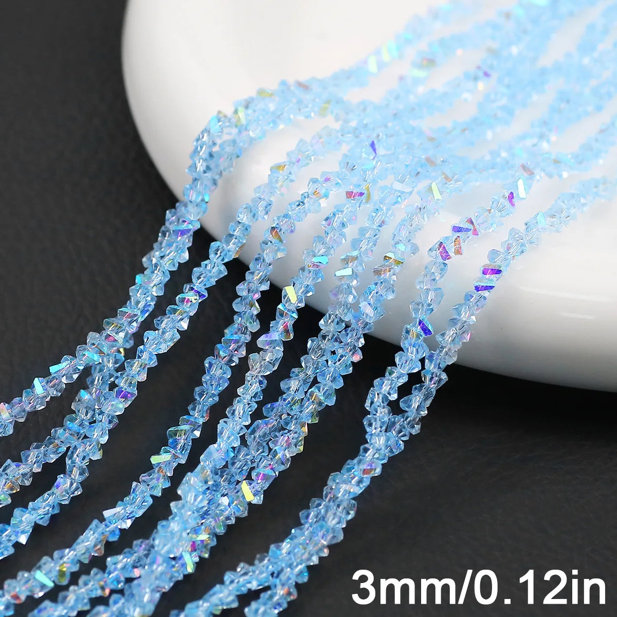 Blue crystal triangle beads strung on thin wire, displayed next to a white dish.