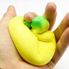 A hand holds a bright yellow squishy banana stress reliever toy with green accents.