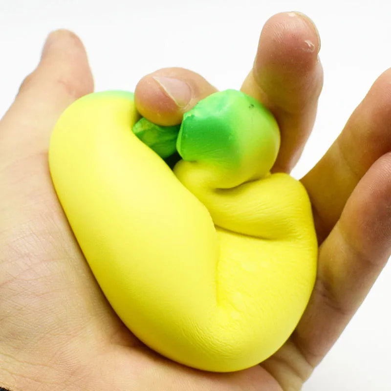 A hand holds a bright yellow squishy banana stress reliever toy with green accents.