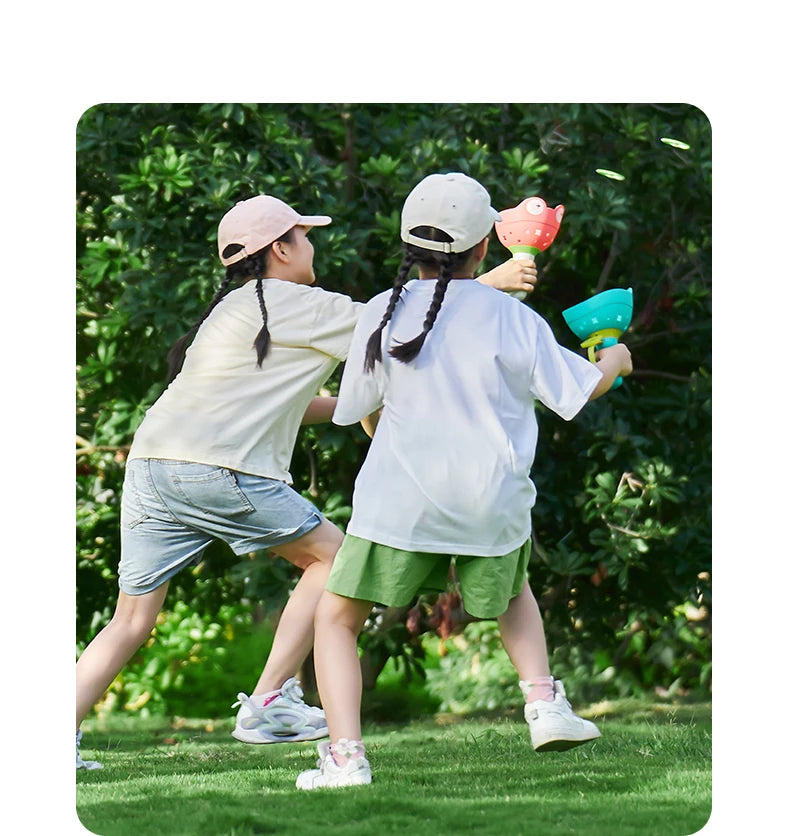 Two children are playing outdoors with a pull-string flying saucer launcher toy.