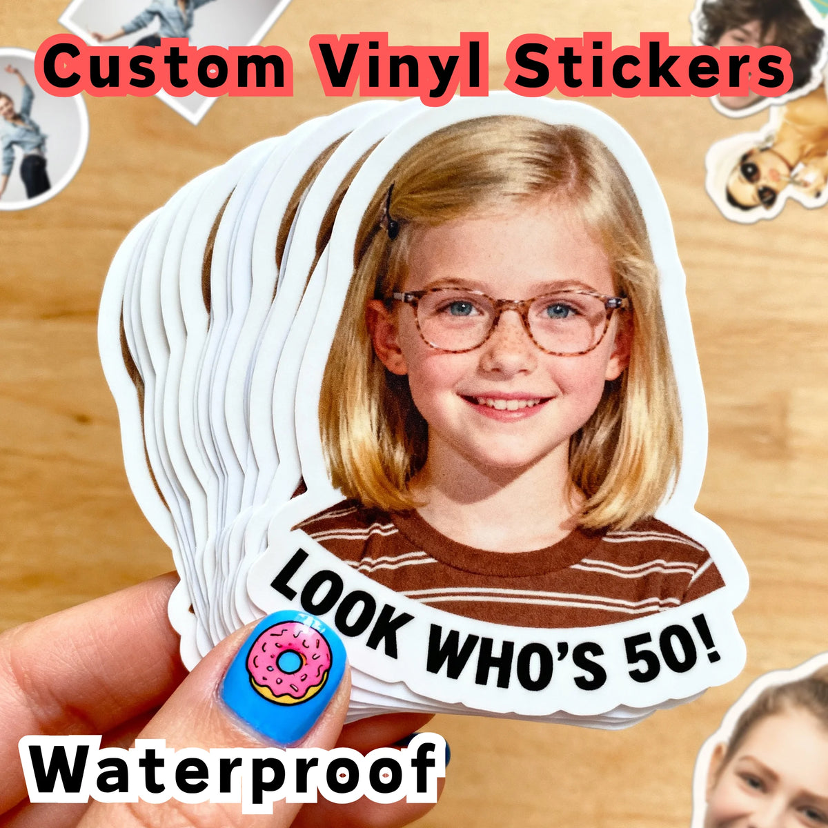 A young girl is smiling while holding a die-cut vinyl sticker featuring her portrait and the text LOOK WHO'S 50!