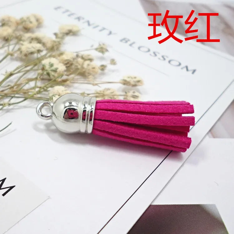 A cluster of bright magenta velvet tassels with silver findings resting on a white surface.