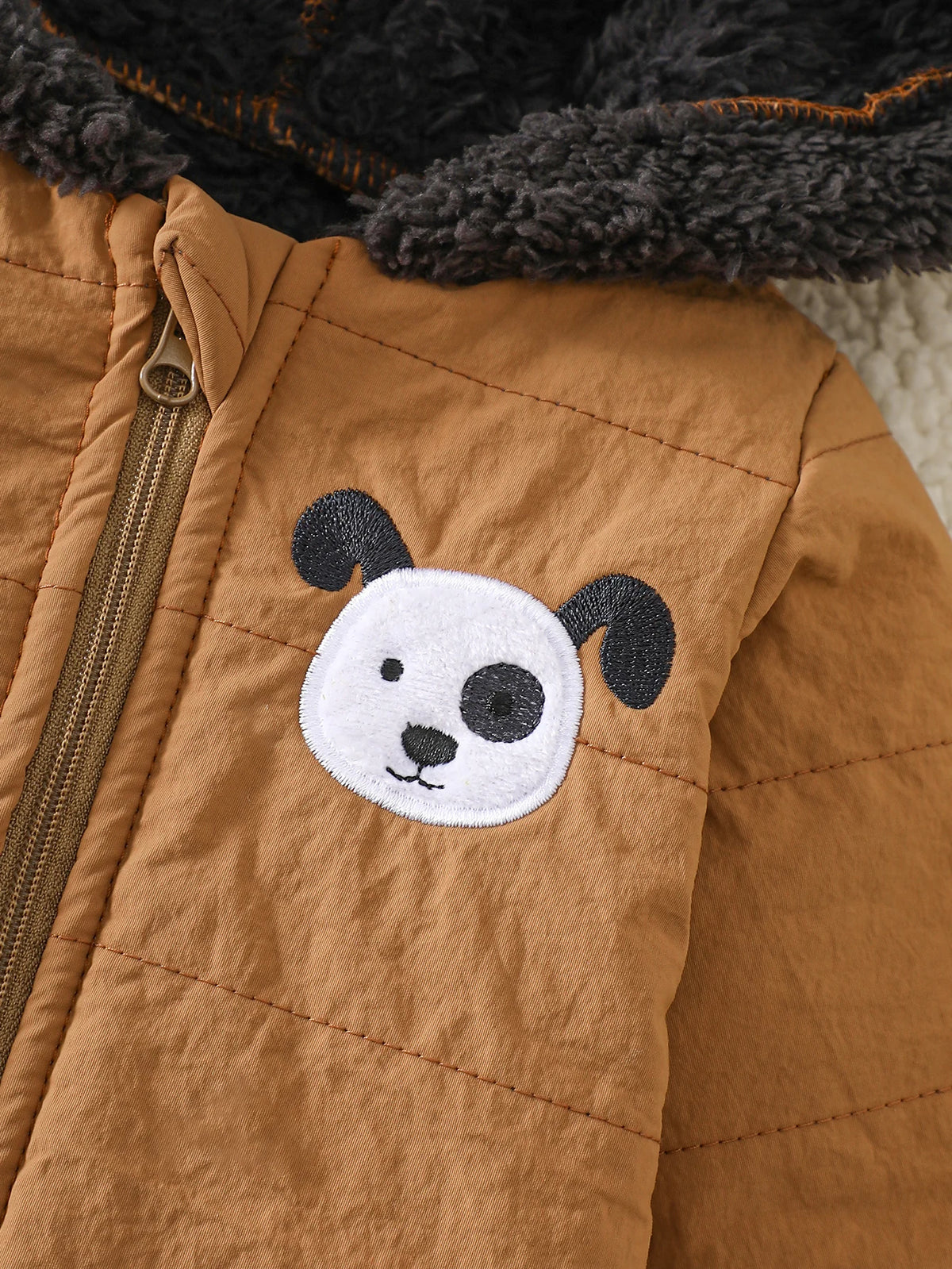 A close-up of a brown fleece jacket with a white panda embroidered patch on the chest.