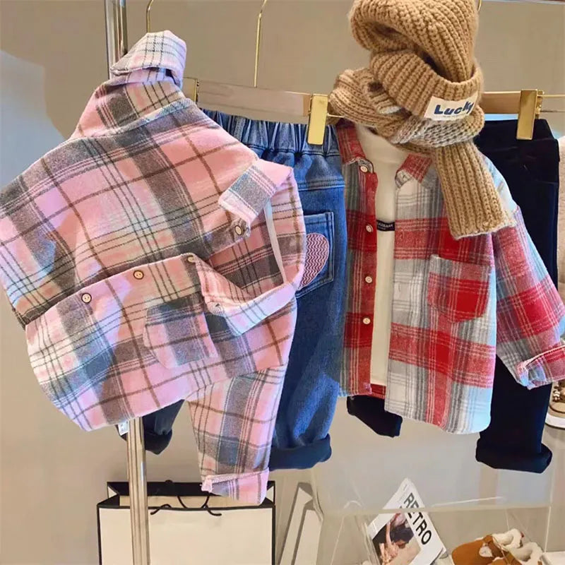 A pink and gray plaid button-up shirt displayed on a hanger next to a brown knitted scarf.
