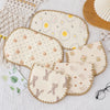 A collection of cute, light-colored fabric pillows featuring various patterns like eggs and animals for newborns.