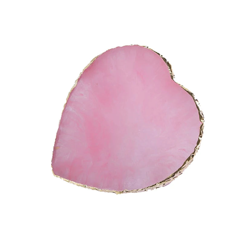 A heart-shaped piece of pink resin with a gold trim.