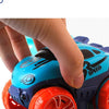 A hand is holding a blue and purple race car track set with orange wheels.