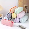 A stack of colorful striped canvas pencil cases in various pastel and bright colors, including pink, yellow, green, and red.