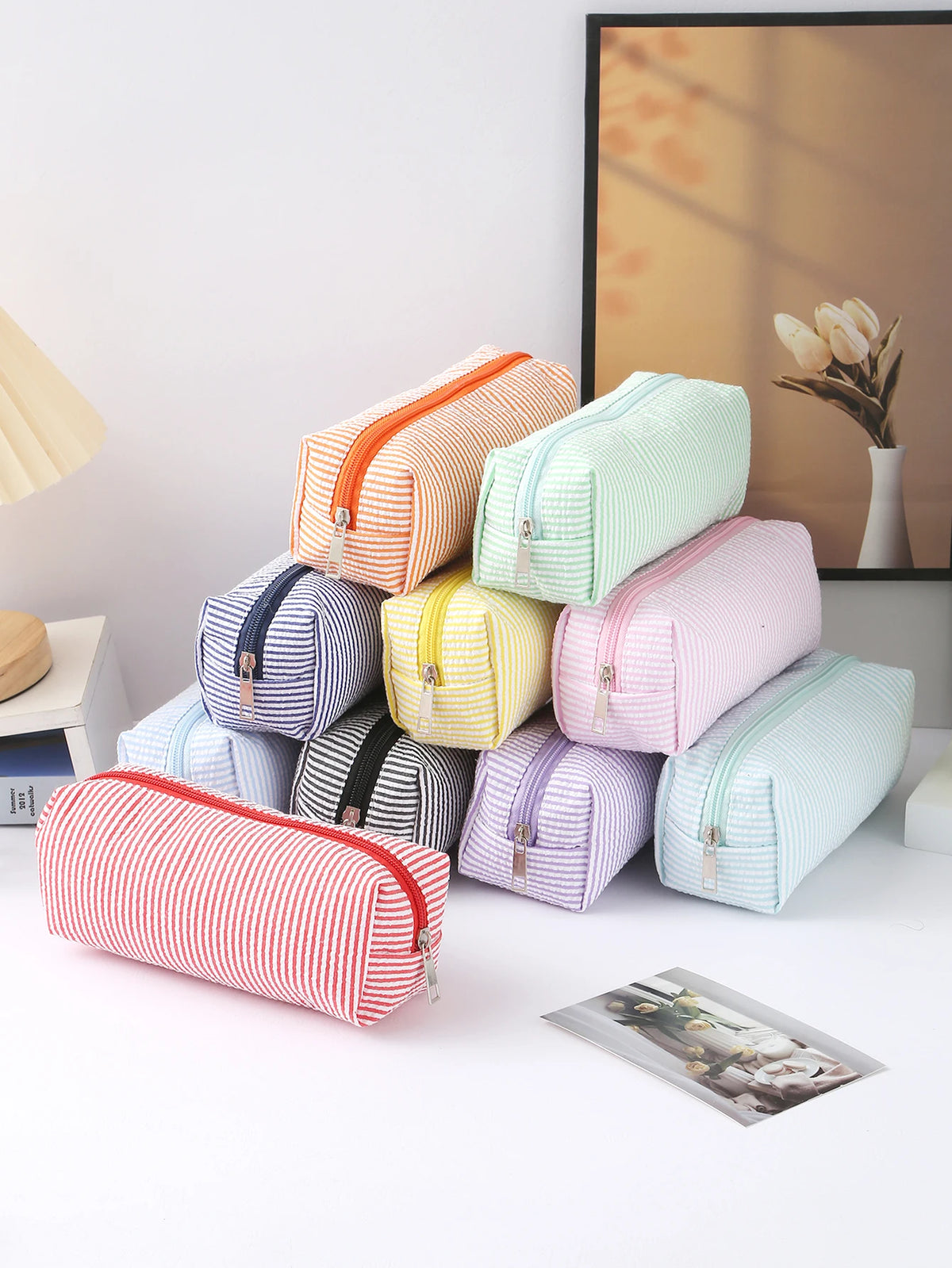A stack of colorful striped canvas pencil cases in various pastel and bright colors, including pink, yellow, green, and red.