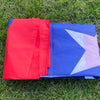 Two folded Puerto Rico National Flags, red and blue with a white star, laid on green grass.