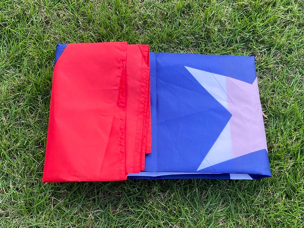 Two folded Puerto Rico National Flags, red and blue with a white star, laid on green grass.