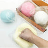 A hand is squeezing a large, yellow squishy stress ball inside a clear plastic bag.