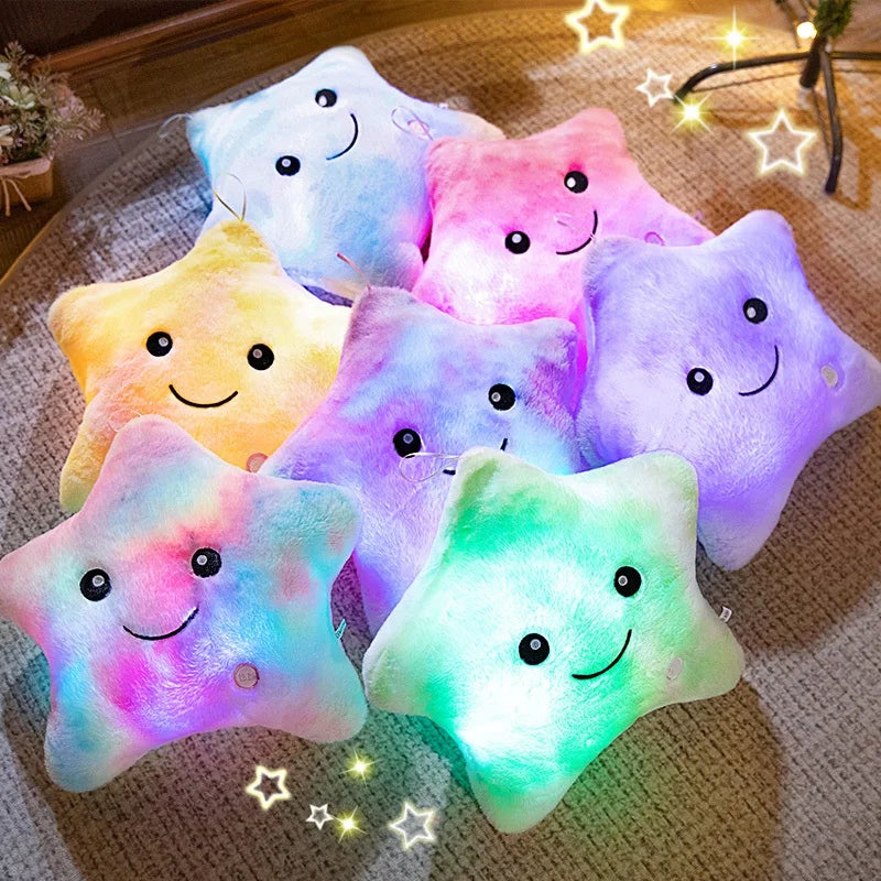 A collection of glowing star-shaped plush pillows with LED lights in various pastel colors resting on a textured surface.