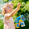 A young girl is blowing bubbles with an electric bubble blower toy outdoors.