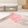 A small, pink, glittery dachshund squishy toy resting on a white plate.