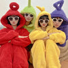 Four adults dressed in colorful Teletubbies-inspired fuzzy hooded pajamas: red, green, yellow, and purple.