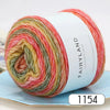 A spool of gradient rainbow yarn is shown rolled up on a light blue surface.