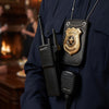 A close-up of a dark blue uniform shirt displaying a police badge and walkie-talkie accessory set.