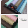 Rolls of linen book binding cloth in various shades of green, purple, and blue fabric.