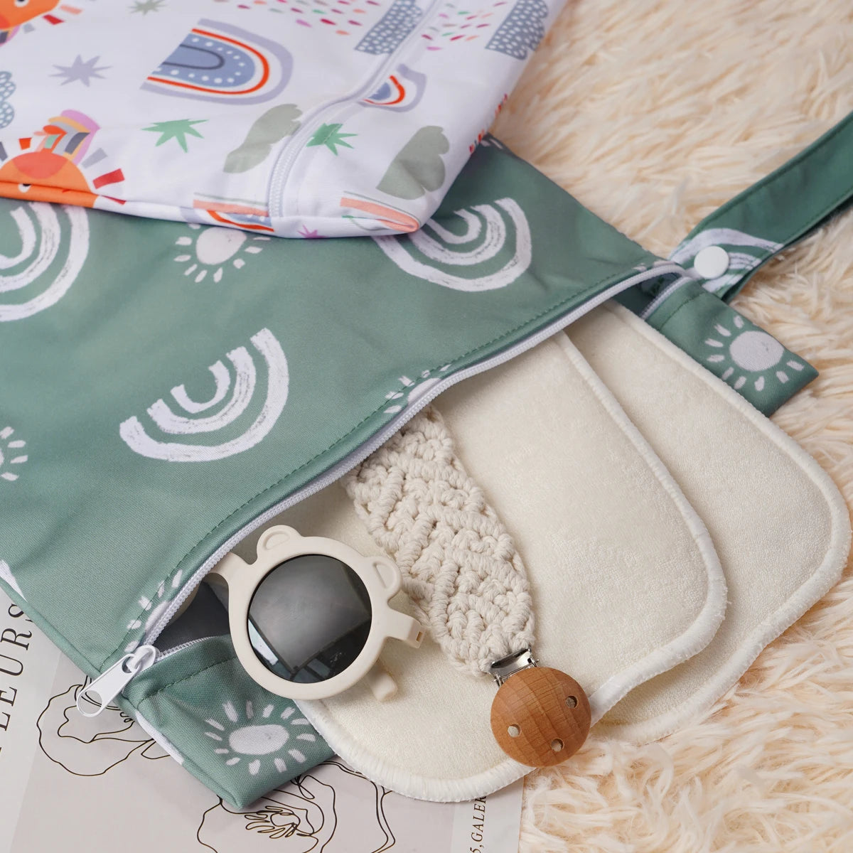Two reusable waterproof baby wet bags featuring colorful rainbow patterns and natural fabric on a light background.