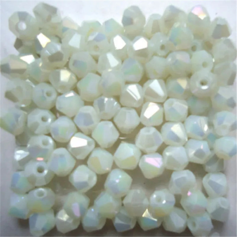A pile of small, faceted glass bicone beads in translucent white and pale iridescent colors.