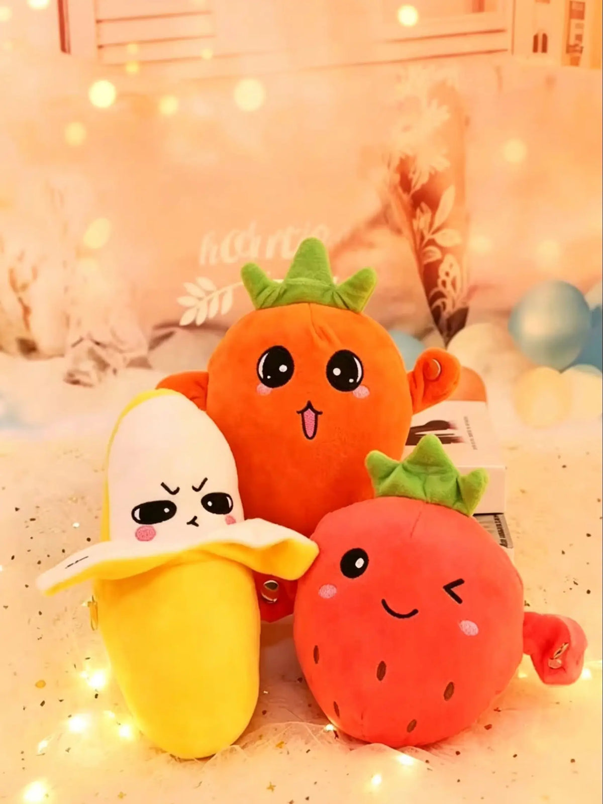 An orange fruit plush toy next to a yellow banana fruit plush toy on a white surface.