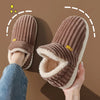 A pair of brown faux fur slippers being held, showing the plush texture and cozy design.