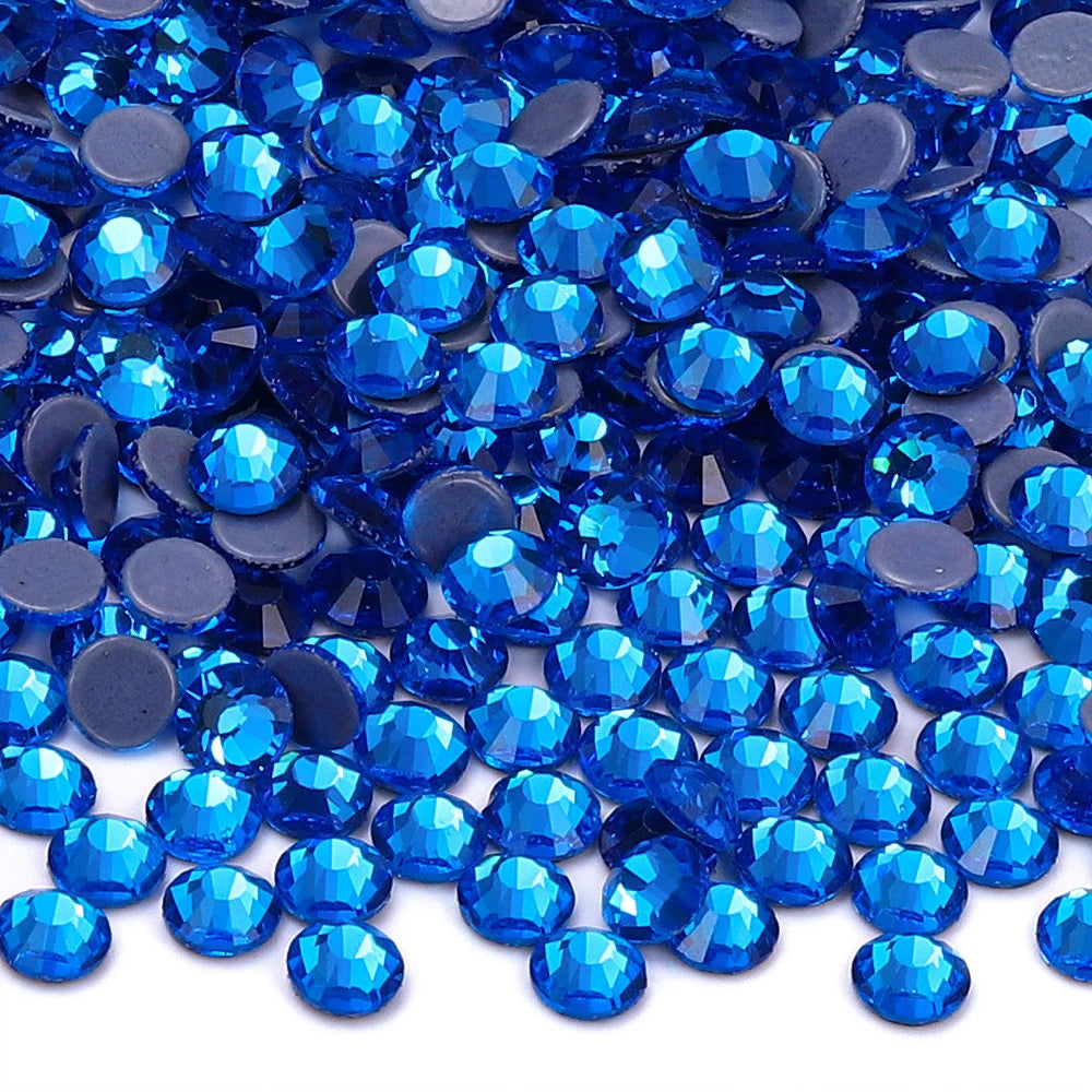 A close-up view of small, round blue glass crystal rhinestones scattered on a white background.