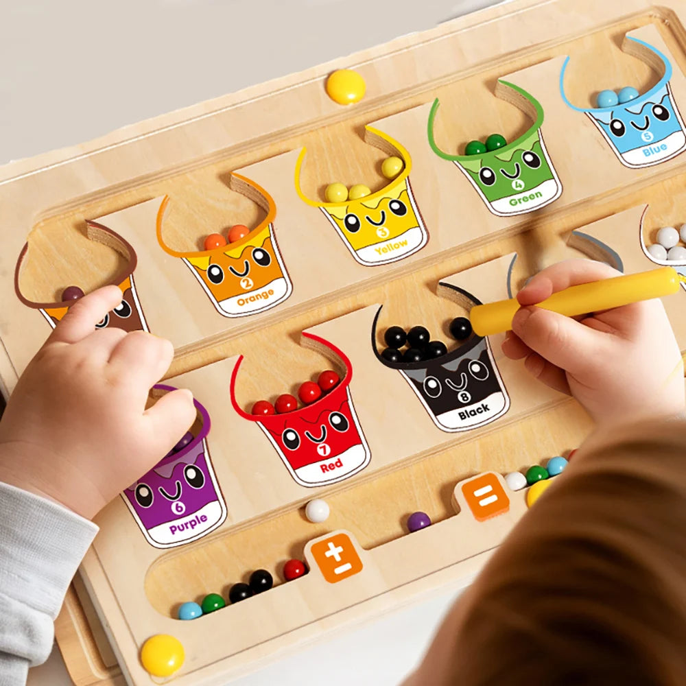 A hand is placing a yellow marker onto a magnetic color and number maze board featuring various colored dinosaur-themed conta