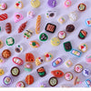 A collection of miniature dollhouse snack foods including candies, jellies, and various small edible items.