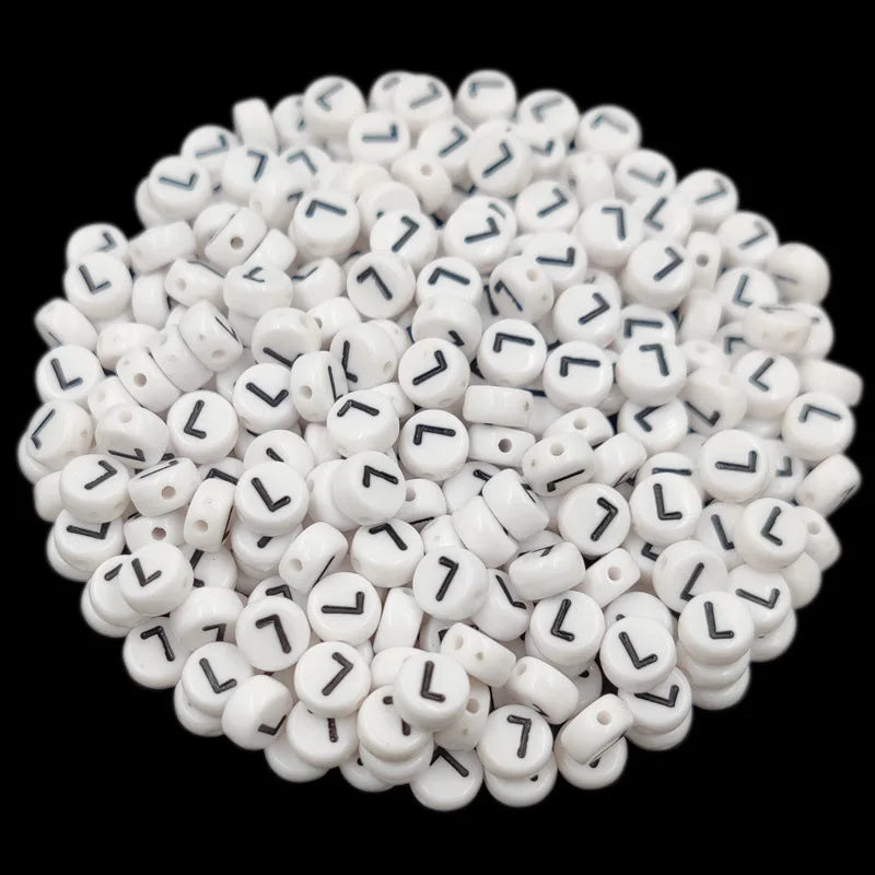 A pile of small white acrylic alphabet letter beads for jewelry making