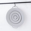 A round, light gray silicone spill stopper lid with concentric rings is hanging from a black rod.