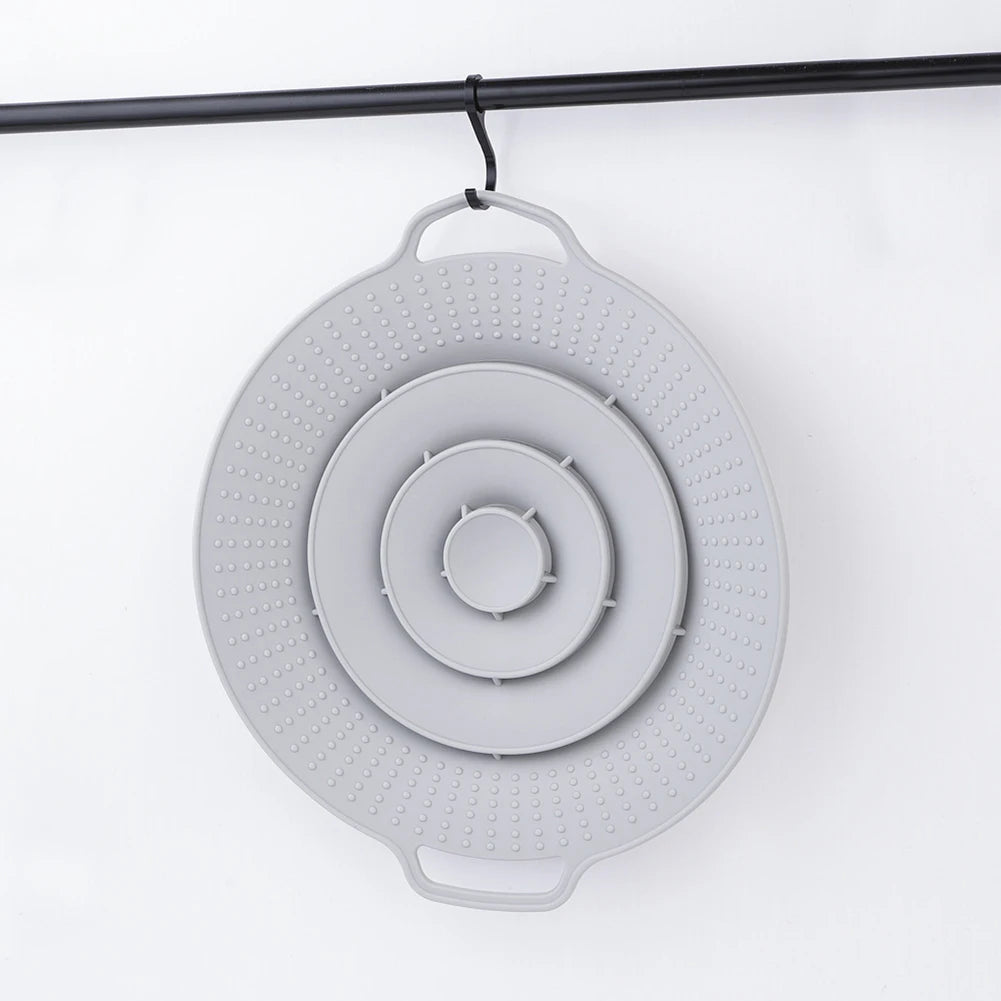 A round, light gray silicone spill stopper lid with concentric rings is hanging from a black rod.