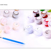 A collection of various acrylic paint colors and brushes laid out for a DIY paint by numbers kit.