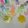 A collection of colorful glow-in-the-dark mini animal figures in various pastel shades arranged on a white surface.